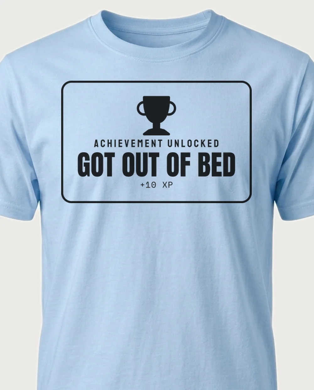 'Got out of bed' — Achievement Unlocked on a light blue tee